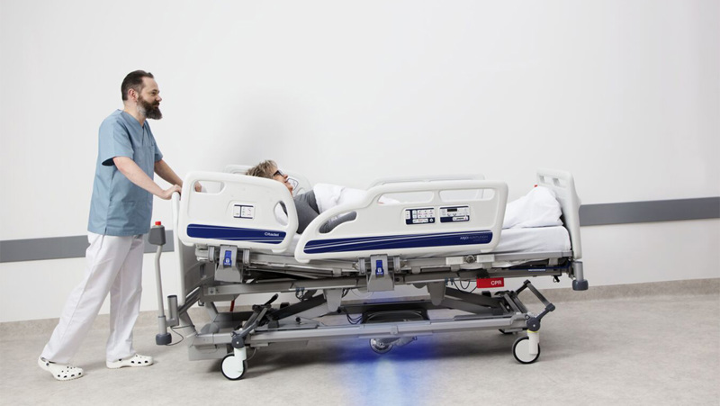 What technologies are used to aid caregivers in transporting patients on hospital beds?