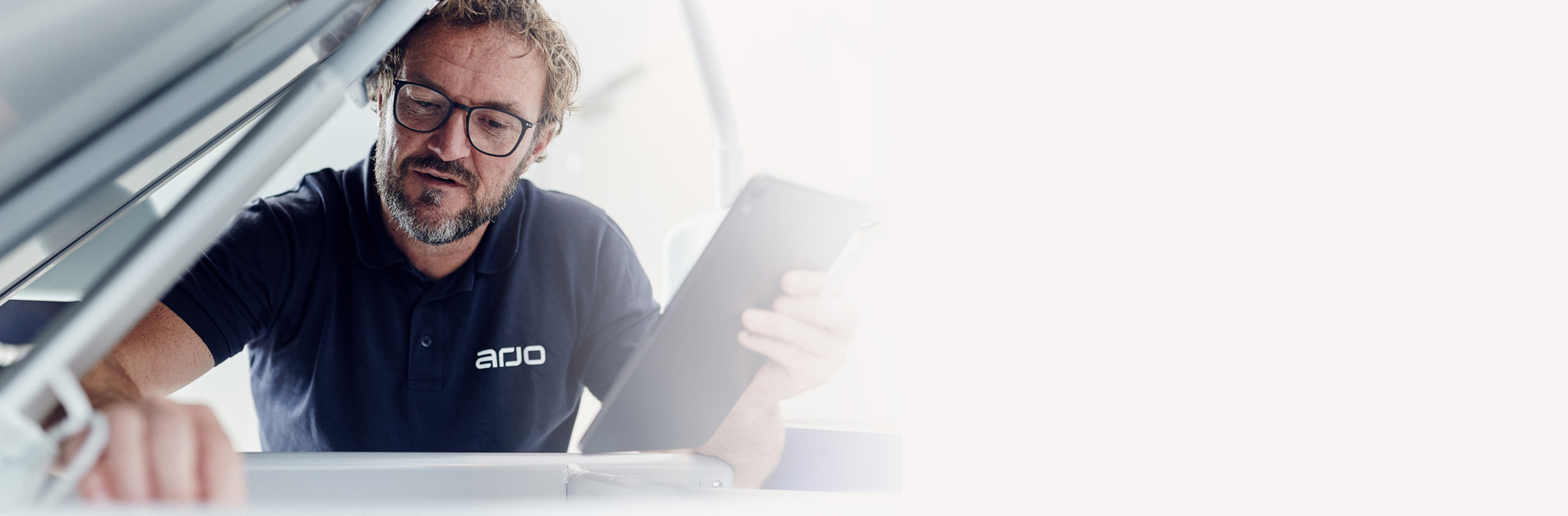 Service technician in branded uniform inspecting medical equipment with a tablet