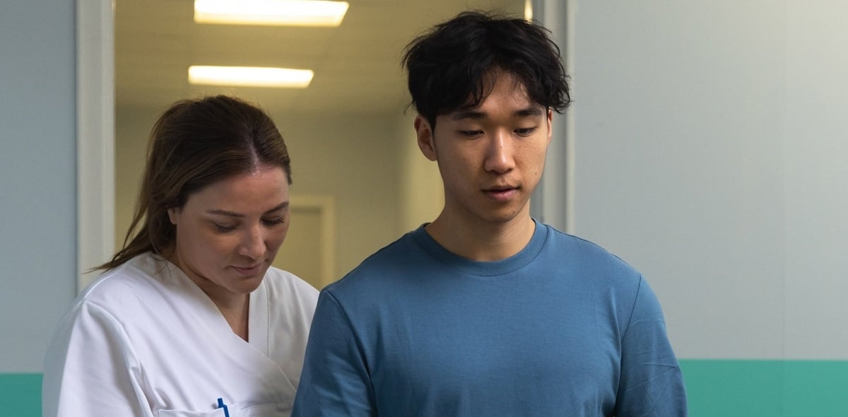 Medical staff supporting a person during physical rehabilitation in a clinical setting