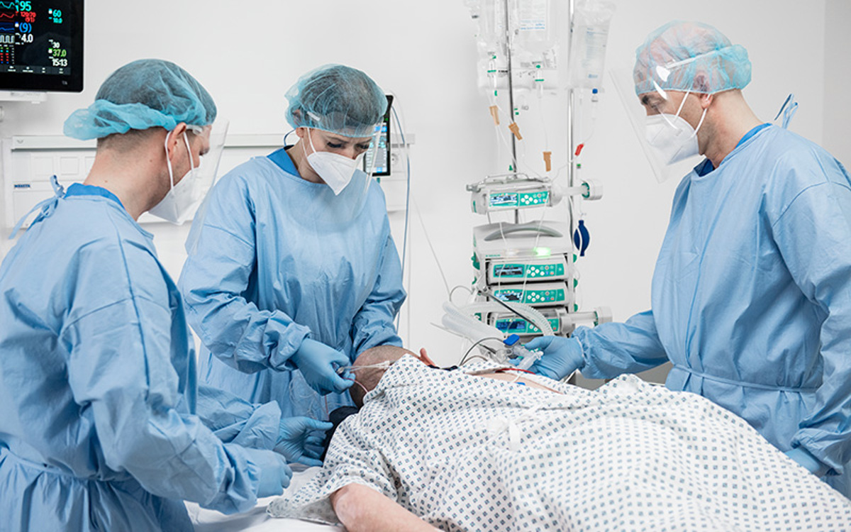 Drei Pfleger mit Patient in Bauchlage